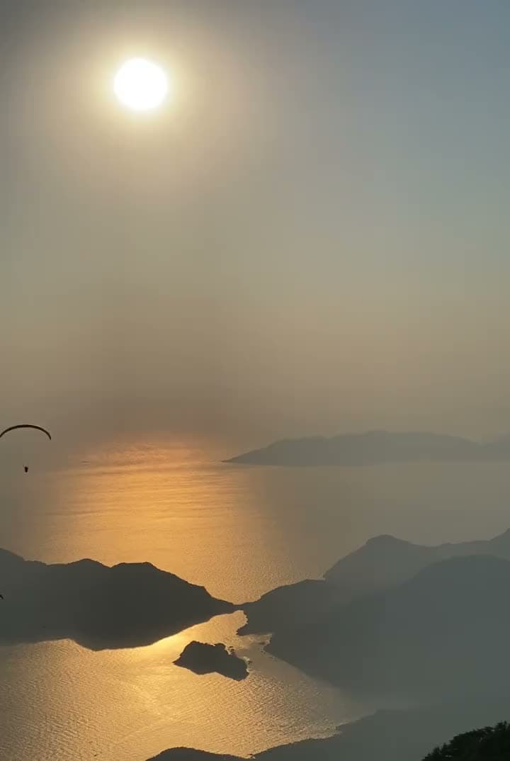 A tandem paraglider over the Ölüdeniz islands at sunset