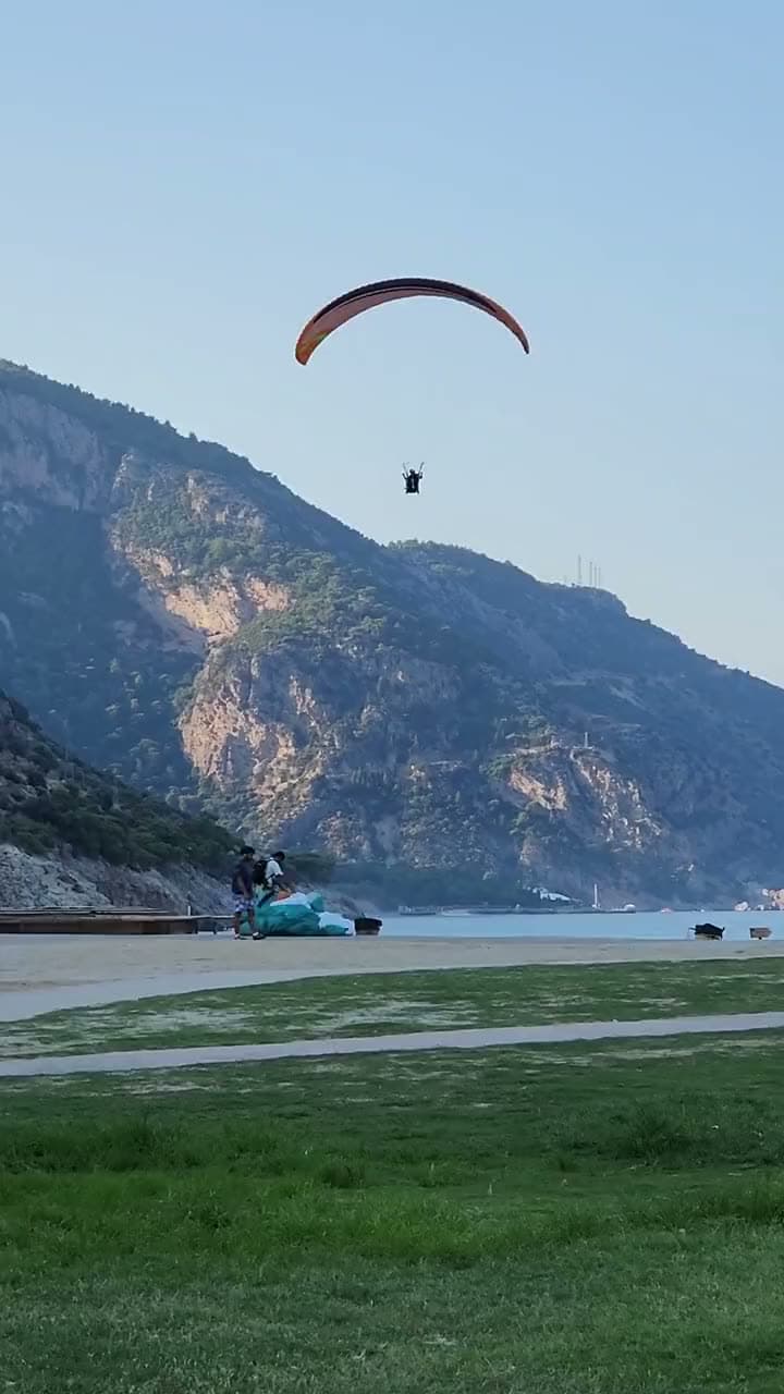 A paraglider coming in to land beneath the steep face of Babadağ