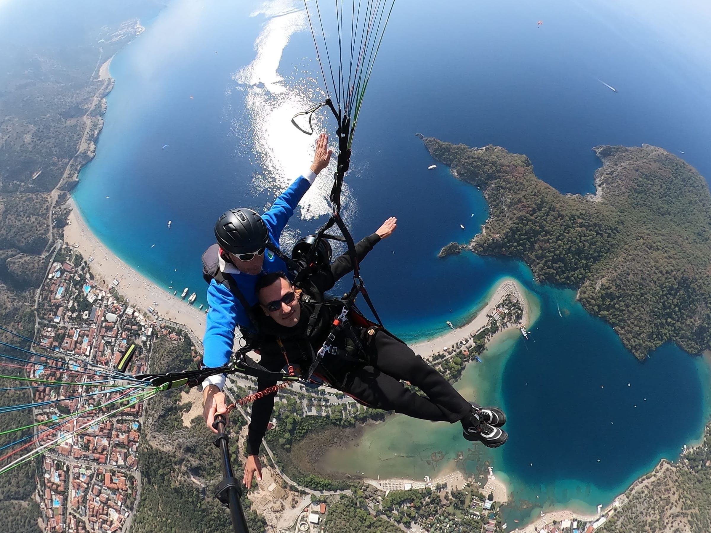 A tandem pilot and passenger with the Ölüdeniz lagoon and Belcekız beach below